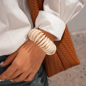 Detail of bohemian acrylic round beaded elastic bracelet on female wrist in urban style