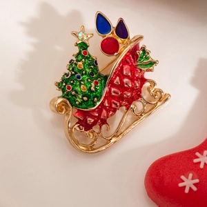 Close-up of gold Christmas sleigh brooch with green rhinestone tree and colorful gifts