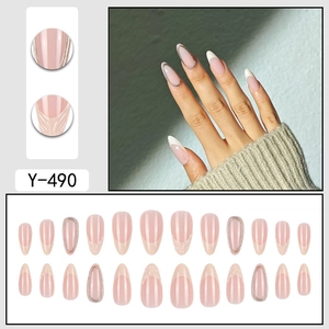 Press-on almond nails with nude pink base, gold French tips, and metallic accents