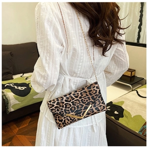 Close-up of leopard print envelope bag with gold V-metal trim worn with lace dress