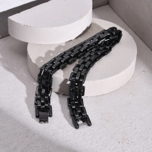 Macro shot of polished black stainless steel link bracelet on geometric display stands
