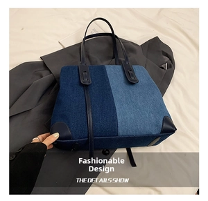 Detail of color-block denim tote bag showing stitching and reinforced leather corners
