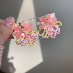 Detail of pink resin flower earrings with pearl center and colorful beaded tassels