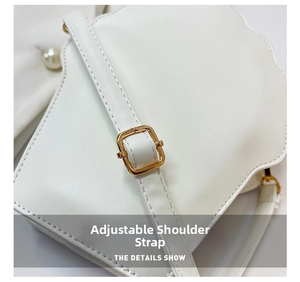 Detail view of the white shoulder bag featuring an adjustable strap with gold buckle