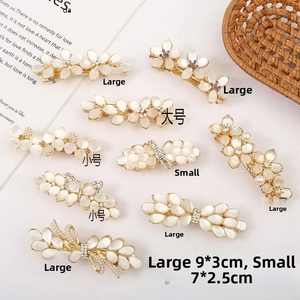Detail view of gold flower hair clips with opal stones and pearls on magazine background