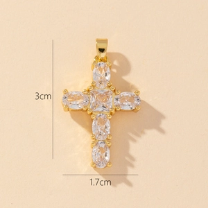Macro detail of gold-plated cross pendant with oval and square cubic zirconia stones