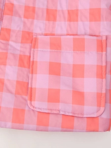 Detail of pink and orange plaid fabric showing stitching on the pocket of the casual set