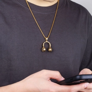 Close-up of a man wearing a golden punk-style headphone pendant necklace on a chain