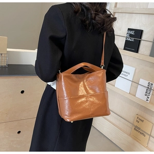 Brown oil wax leather bucket tote bag shown with model in a minimalist library setting