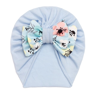 Close-up of light blue baby turban hat featuring a detailed floral print bow decoration