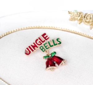 Detail of enamel red Christmas bells brooch with Jingle Bells lettering and green leaves