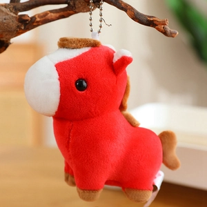 Detail of red plush pony keychain with metal chain hanging on a natural wood branch
