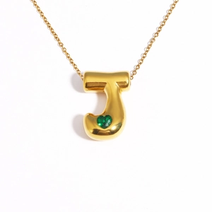 Detail of 18k gold plated bubble letter J necklace with a green heart gemstone pendant