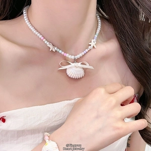 Détail d'un collier de perles avec étoiles de mer et pendentif coquillage avec nœud