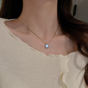 Elegant gold square necklace with blue pearlescent inlay worn by a female model