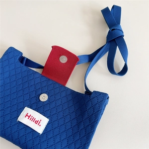 Blue knitted crossbody bag with diamond texture, red magnetic strap and Hilldi logo label
