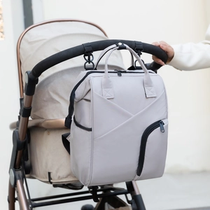 Light grey multi-functional diaper bag hanging on a stroller with durable straps