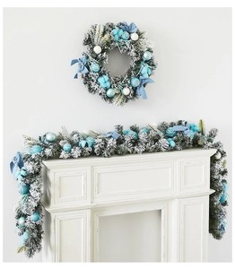 Close-up of frozen white Christmas garland with blue ornaments and snowy pine needles