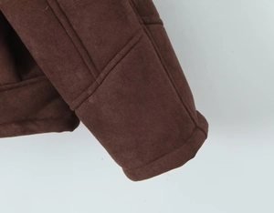 Vue macro détaillée du tissu en daim marron et des coutures soignées sur le poignet de manche