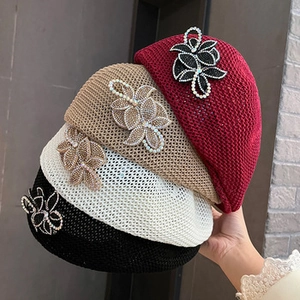Close-up of knit beret with mesh texture and sparkling rhinestone flower accents