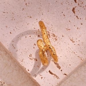 Macro detail of golden irregular hammered texture on retro minimalist steel earring