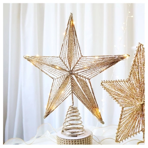 Macro detail of gold glittery Christmas tree topper with warm glowing LED lights and spring base