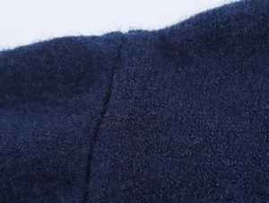Close-up of navy blue long-fiber knit fabric showing mohair-like fuzzy texture and seams