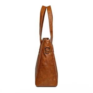 Side view of a brown leather tote bag with metallic D-ring and reinforced stitching
