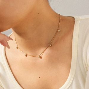 Elegant gold stainless steel necklace with round zircon charms on a model's neck
