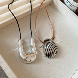 Detailed macro view of silver horseshoe and shell pendants in a luxury gift box
