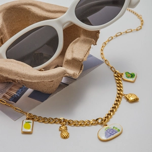 Détail du collier en acier inoxydable 18K avec breloques de fruits en émail sur fond blanc