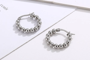 Macro shot of silver beaded hoop earrings featuring polished metallic round spheres