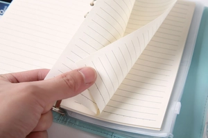 Close-up of A6 binder notebook showing cream-colored lined paper and PU leather cover
