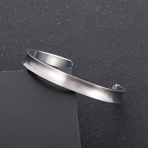 Macro view of minimalist silver stainless steel cuff with concave brushed metal finish
