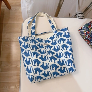 Close-up of canvas tote bag featuring cute blue cat patterns and simple wish label