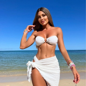 Textured white bandeau bikini and matching sarong set against a tropical beach background