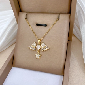 Close-up of gold-plated titanium necklace with angel wing, heart, and star charms in a box