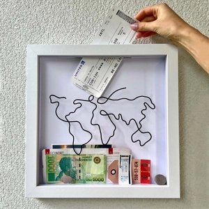 Detail of putting a travel ticket into the white wooden world map souvenir shadow box