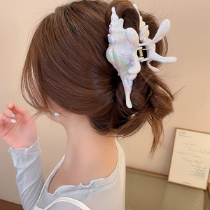 Detail of pearlescent shell hair claw clip styled on a brunette bun for a chic look