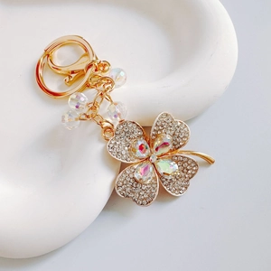 Detailed close-up of golden four-leaf clover keychain with colorful crystals and rhinestones