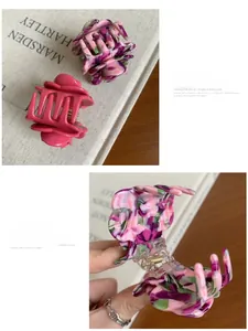 Close-up of marble acetate rose hair claw clip and fuchsia shark clip with gold logo