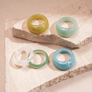 Colorful geometric acrylic resin rings displayed on textured stone platforms