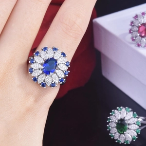 Exquisite flower-shaped ring with 2-carat blue oval sapphire and side crystals on a model