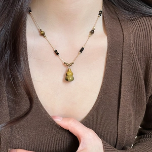 Detailed close-up of zircon tiger eye tassel necklace on model with vintage brown tones