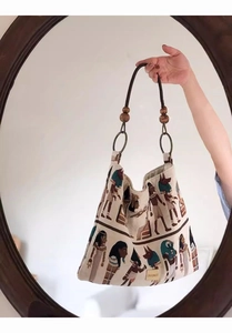 Close-up of vintage jacquard tote bag with Egyptian pattern and wooden bead detail