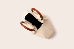 Top-down view of a beige ruched cloud bag featuring a brown round handle and magnetic closure