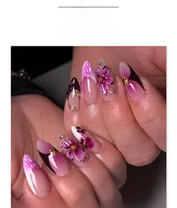 Détails macro d'ongles amande avec fleurs 3D violettes et accents de perles dorées