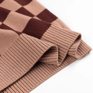 Détail de maille à damier avec ourlet côtelé montrant les motifs marron et beige