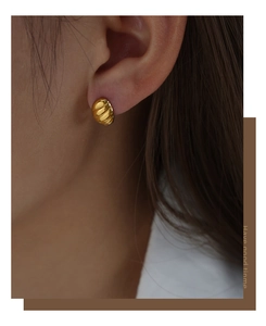 Detailed view of gold plated titanium steel C-shaped twisted earrings on model's ear