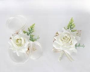 Close-up of elegant wedding boutonniere and wrist corsage set with white roses and greenery